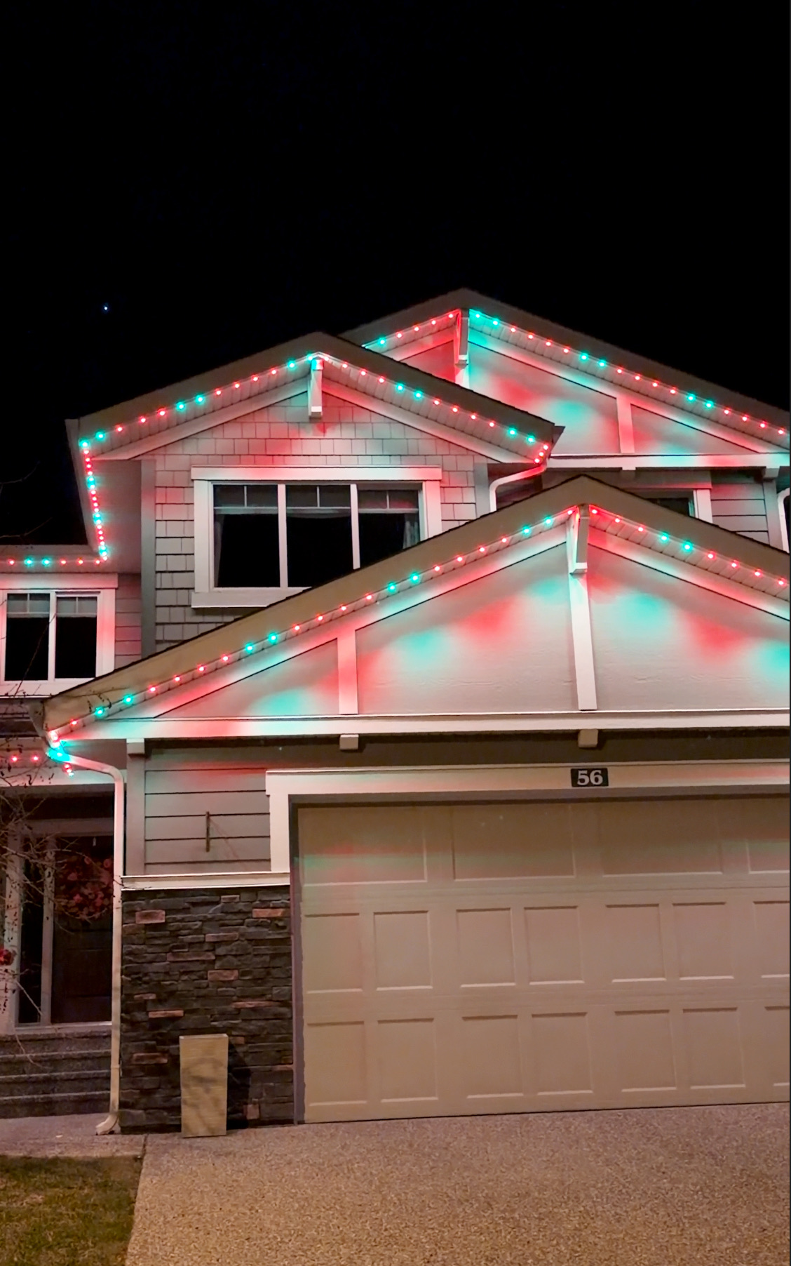 Colorful permanent holiday lights glowing on a snowy Calgary roofline